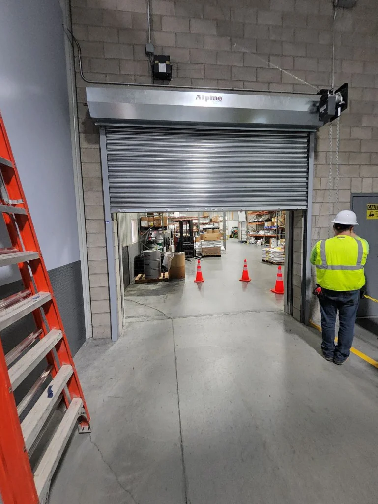 Technician testing fire-rated rolling steel doors in an industrial facility